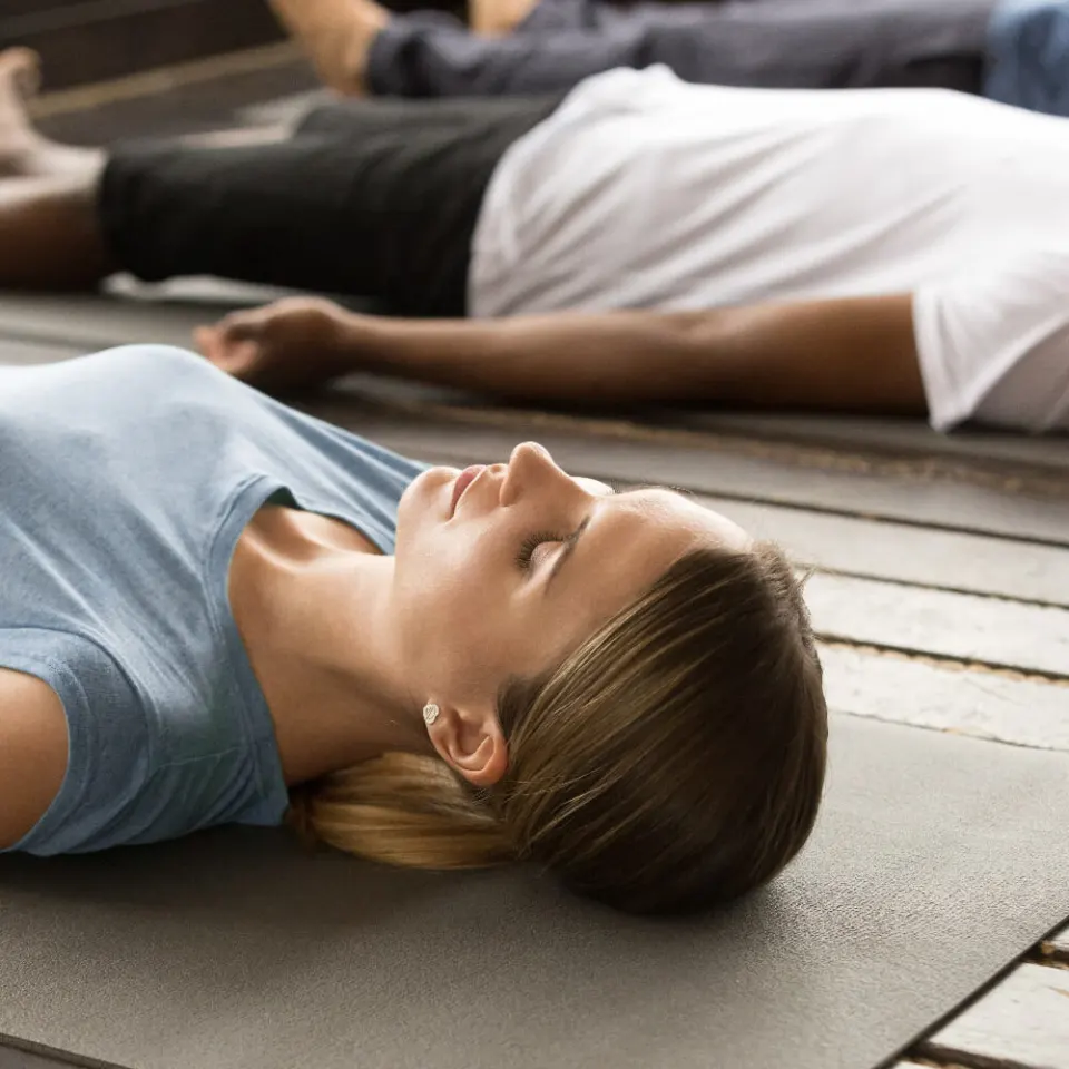 A student lying on a yoga mat in deep relaxation