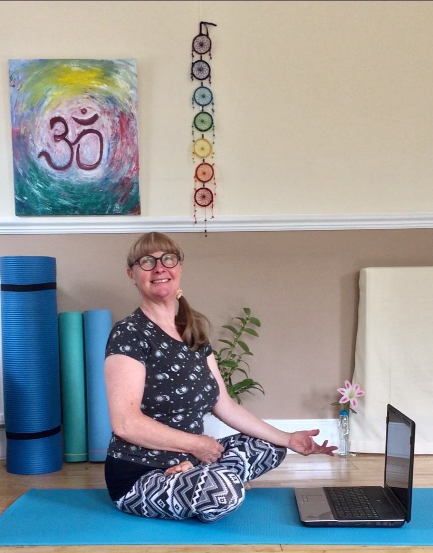 Susan sitting cross-legged on her mat, ready to teach